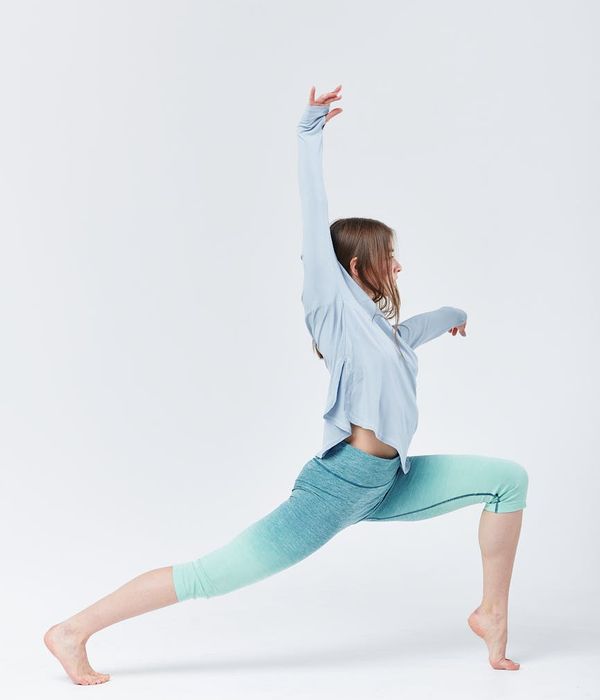 Woman performing a dynamic stretching exercise in a bright, modern space.